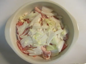 耐熱皿に豚肉、玉ねぎ、にんにくを重ねる。