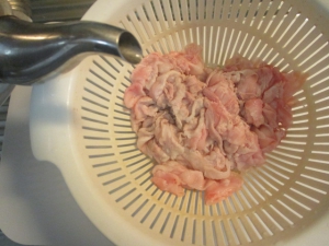 豚肉に熱湯をかけて余分な脂を落とす